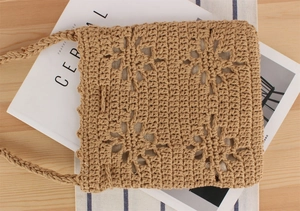 Flat lay of hand-crocheted hollow floral tote bag on wooden desk with vacation vibe