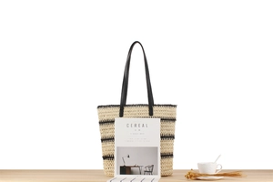 Détail macro du sac cabas tissé à rayures avec anses en cuir sur table épurée