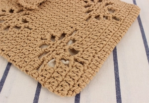 Macro detail of hand-woven cotton rope handbag featuring intricate hollow flower patterns