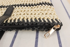 Détail du sac de plage tressé montrant la fermeture éclair noire et les ferrures dorées
