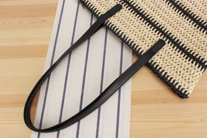Détail d'un sac cabas en paille tissé main avec rayures noires et anses en similicuir