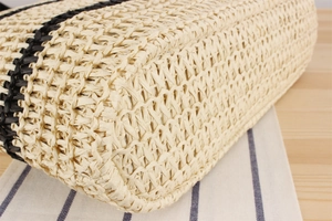 Détail du sac en paille tressé main montrant le fond renforcé et la texture rayée