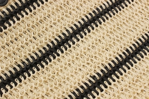 Détail macro du sac de plage tissé main avec textures diagonales beige et noir