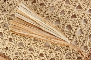 Détail macro de pendentifs à franges en paille faits main sur un sac bohème