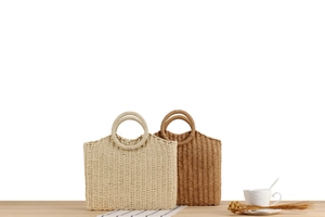 Detail of handmade woven handbags in beige and tan colors with circular handles