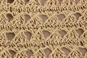 Gros plan détaillé du tissage en maille losange sur un sac cabas en paille beige