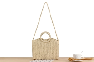 Detailed texture of beige woven shoulder bag with round handles on a wooden table