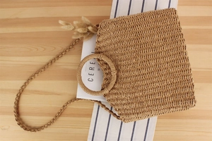 Close-up of the woven texture and round wooden handle of the handmade straw handbag