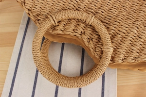 Detailed macro view of woven straw handbag with a round handle and natural fiber texture