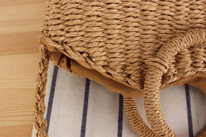 Close-up of handmade woven straw bag with round handle and fabric drawstring lining
