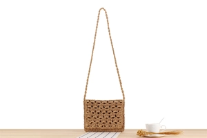 Detail of handcrafted paper rope crossbody bag with scalloped crochet pattern and straw strap