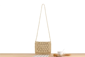 Detail of handmade woven paper rope crossbody bag with shell pattern flap on wooden desk