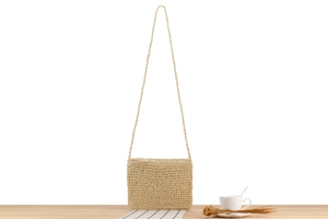Detail of minimalist handmade paper rope crossbody bag with woven texture on wooden desk