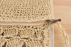 Macro detail of hand-woven paper rope bag showing metal zipper and inner lining texture
