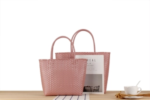 Detailed view of pink woven plastic picnic bags in two sizes on a wooden table
