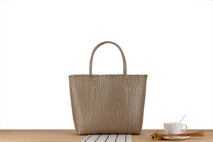 Close-up of dark brown handwoven tote bag with dense checkerboard texture on wooden table