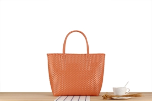 Close-up of orange woven plastic picnic tote bag texture with rounded handles