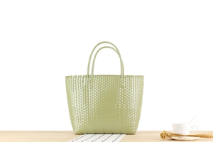 Detail of the woven texture on a light green Macaron style plastic picnic tote bag