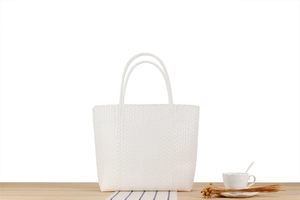 Detailed view of white woven plastic picnic tote with fine grid texture and sturdy handles