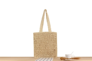 Close-up of beige hand-woven tote bag showing detailed hollow mesh texture and wide handles