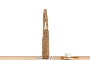 Side view detail of handmade woven straw shoulder bag in natural khaki fiber