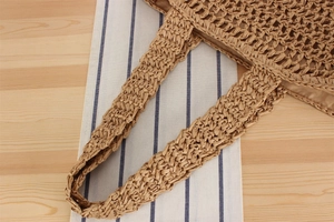 Macro shot of the straw woven handbag showing the hollow crochet pattern and shoulder strap
