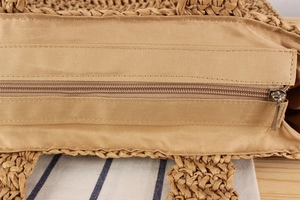 Detailed close-up of woven straw bag showing natural texture and silver zipper closure