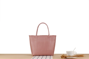 Macro detail of dusky pink woven plastic tote bag with textured cross-weave pattern