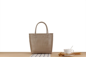 Close-up of khaki woven tote bag showing texture and handle details on a table