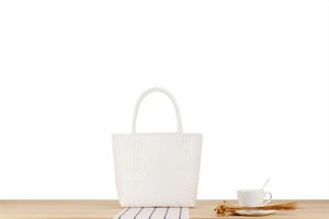 Detail of the cross-weave pattern and handle of this white woven picnic handbag