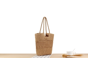 Detail of hollow woven paper rope tote bag with brown fabric lining and shoulder straps