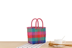 Gros plan d'un panier de pique-nique coloré tressé à la main sur table en bois