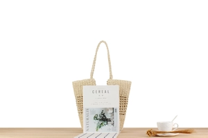 Detail of hollow woven paper rope shoulder bag on a wooden table for beach vacations