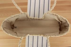 Detailed interior of woven straw beach tote featuring zipper closure and fabric lining