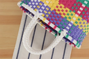 Vue de dessus d'un mini sac à main tressé en plastique multicolore sur bois naturel