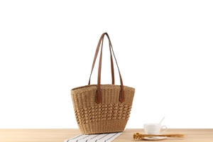 Macro detail of hand-woven straw tote with hollow pattern and brown leather straps
