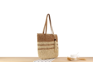 Détail du sac cabas en paille tissée avec rayures dégradées et pompon en perles