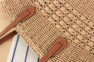 Macro detail of hand-woven tote bag with brown leather handle and white stitching