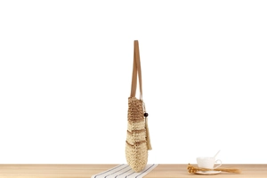 Gros plan d'un sac cabas rayé en corde de papier avec bandoulière en cuir et gland