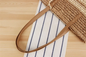 Détail d'un sac tissé en corde de papier rayé avec des anses en cuir marron et coutures