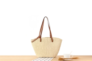 Detail of hand-woven paper rope tote with brown leather strap and decorative knot