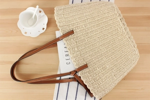 Detail of woven paper rope tote bag with wavy edges and brown leather shoulder straps