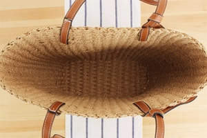 Top view showing the spacious interior and brown leather handles of the woven straw tote bag