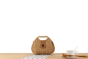 Detailed close-up of woven paper rope bag with brown leather strap and gold metal buckle