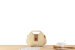 Close-up of wavy paper straw handbag with brown leather clasp and metal lock details