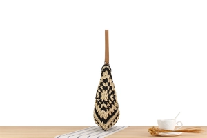 Detail of hand-woven crochet tote with black and white floral pattern and leather strap
