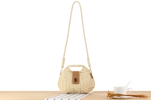 Detail of paper straw woven bag featuring a brown leather buckle and metal lock clasp
