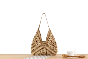 Close-up of dual-tone woven paper rope tote bag with leather strap on a table