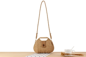 Detail of paper rope woven handbag with brown leather flap and gold metal clasp closure