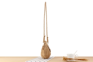 Detail of paper rope woven crossbody bag with leather trim and gold-tone hardware